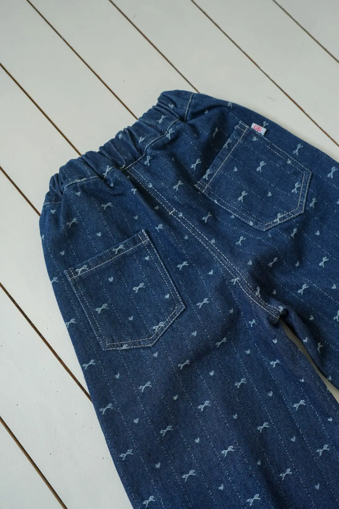 image: Bow Denim Jeans for girls with delicate bow print and ruffled cuffs