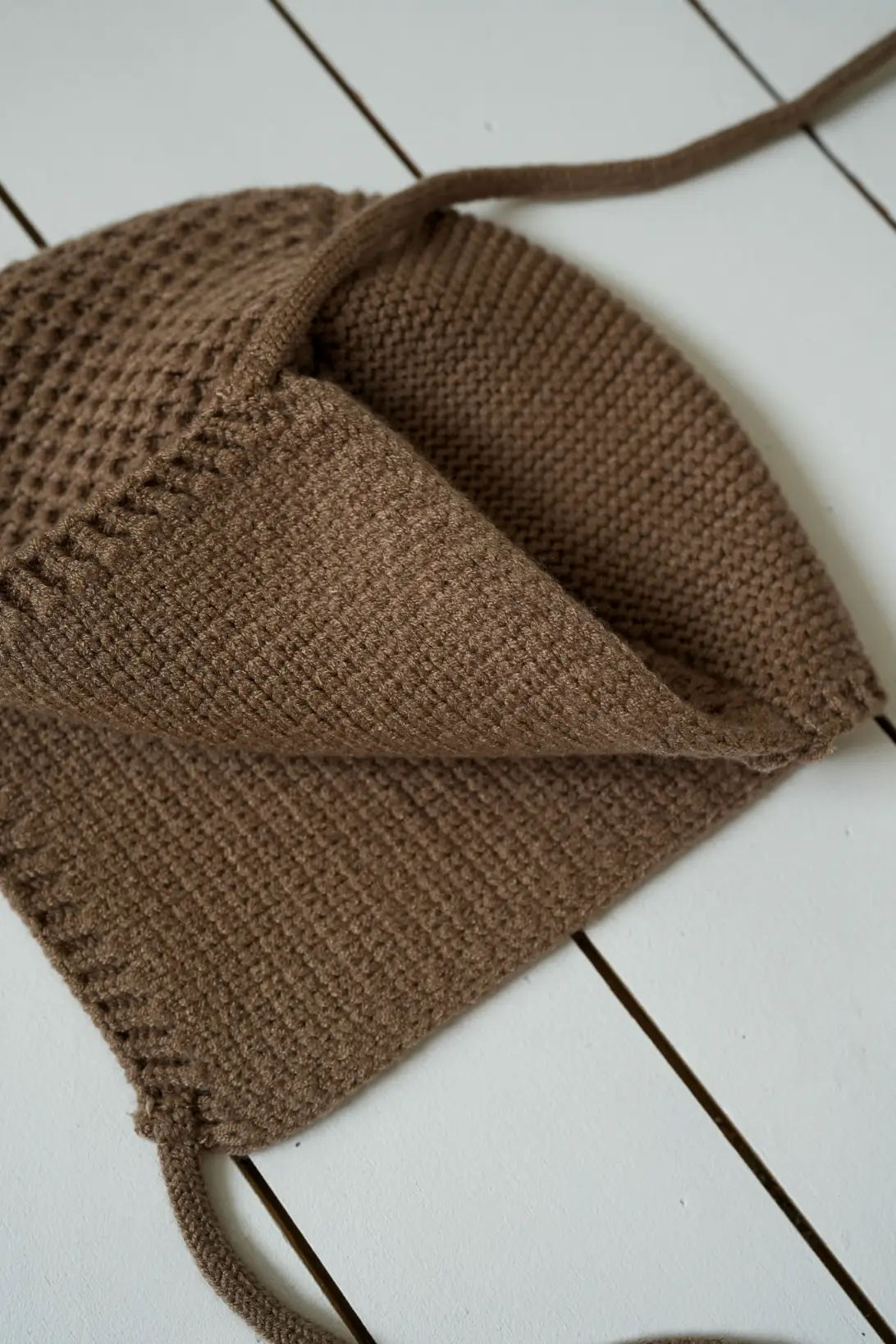 Soft textured knit detail of brown baby bonnet